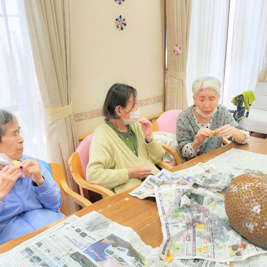 ジャックフルーツを囲んで召し上がっている利用者さまたち