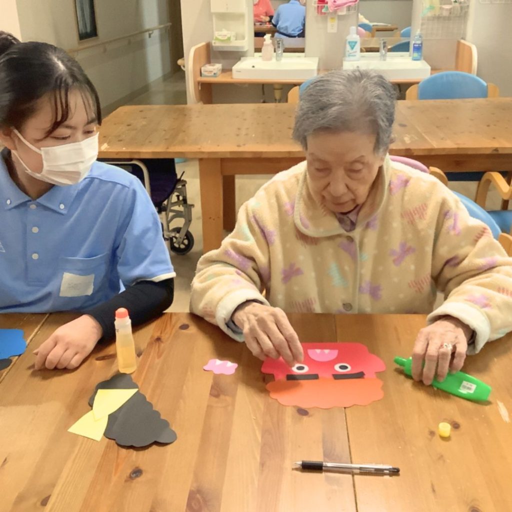 鬼のお面を作る利用者さまと介護学生さん