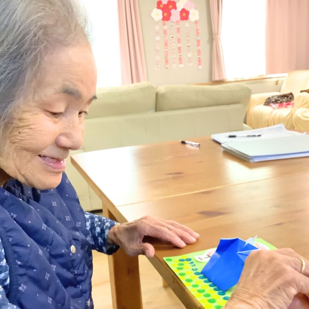 折り紙の雛人形を貼り付けている利用者さま
