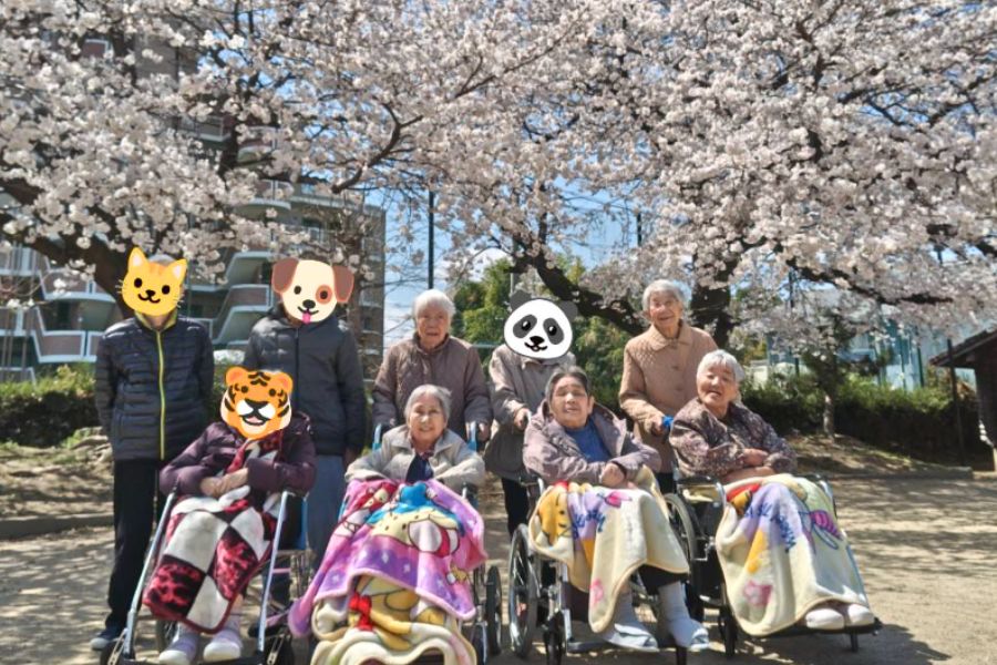 桜の下で集合写真を撮る利用者さま